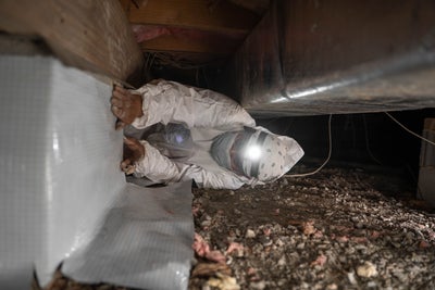 Crewman installing vapor barrier in a crawl space.
