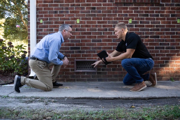 JES Foundation Repair inspector and homeowner pointing at crawl space door