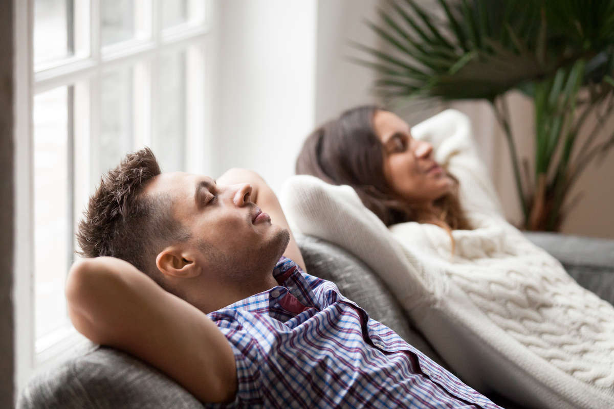 man and woman arms behind heads relaxing on couch