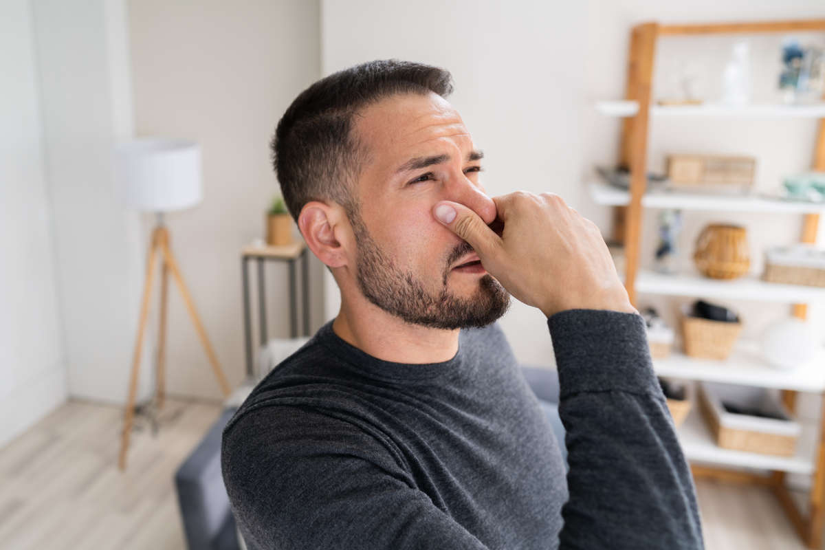 man holding nose bad smell