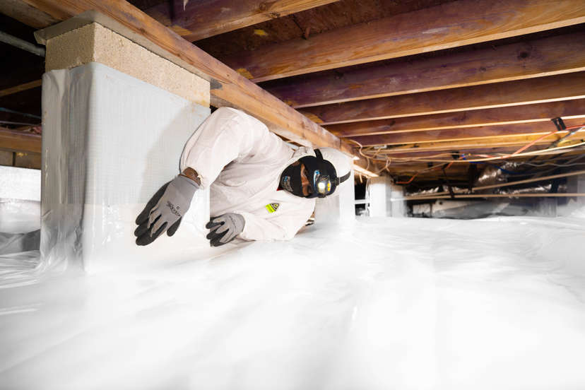 man installing crawl space encapsulation vapor barrier