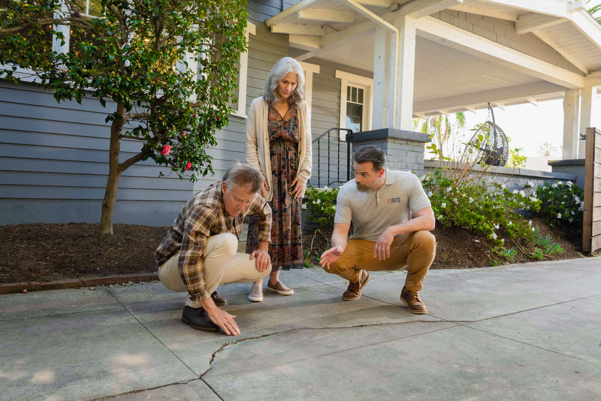 inspector showing two homeowners concrete driveway slab crack