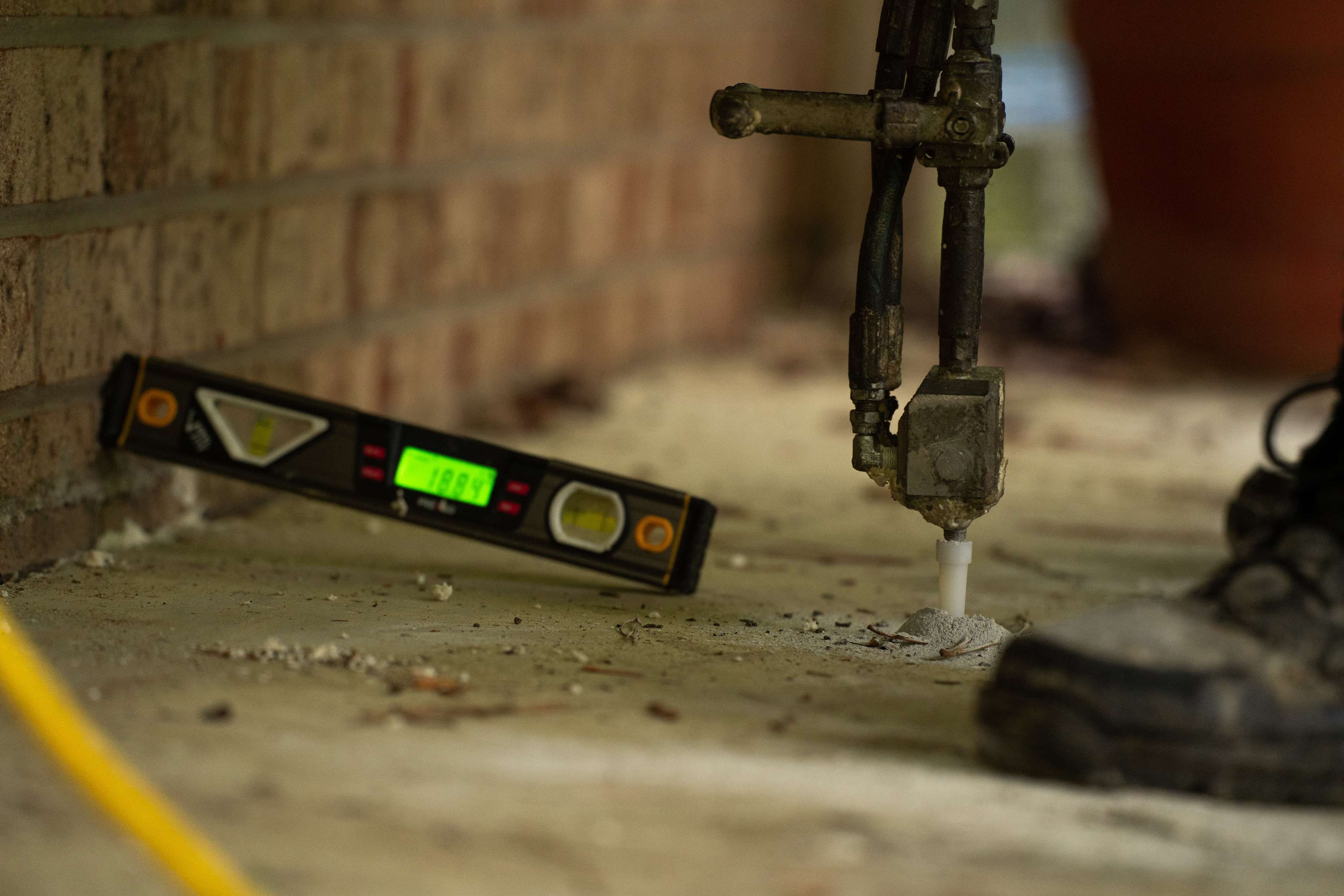 crew member with level installing polyurethane foam to fix a sinking concrete slab