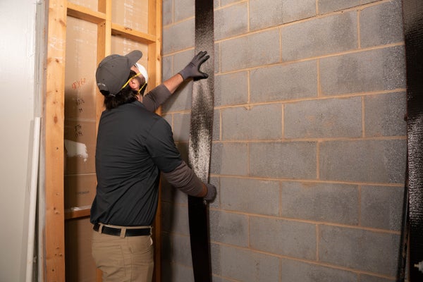 man installing carbon fiber repair in basement