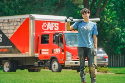 Smiling AFS worker holding a section of a push pier, standing in front of a company vehicle