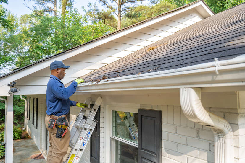 inspector on ladder looking at house roof