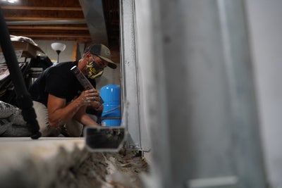 crew member installing an interior basement drainage system