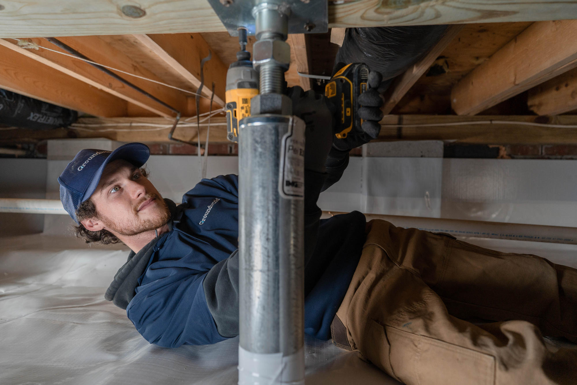 JES Foundation Repair Groundworks crew member installing IntelliJack crawl space system