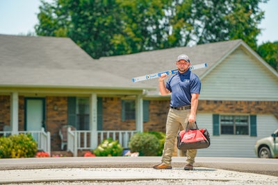 Inspector in front of home with tools.