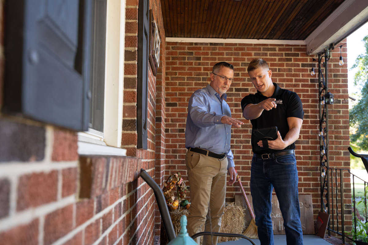 JES Foundation Repair inspector with laptop and homeowners sitting at a table