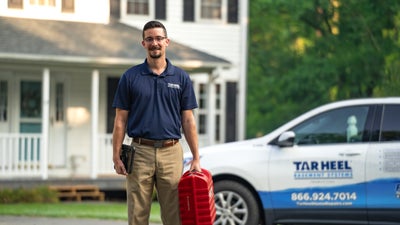 Tar Heel Basement Systems inspector standing by a house and a company vehicle