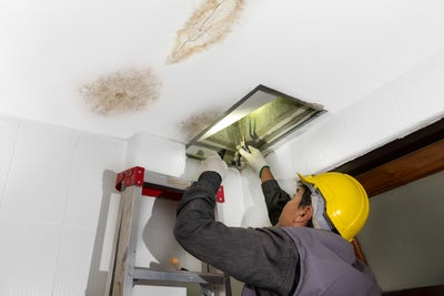 man fixing plumbing in ceiling the caused water damage and ceiling cracks