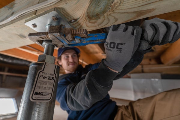 Groundworks crew tightening crawl space jack with wrench