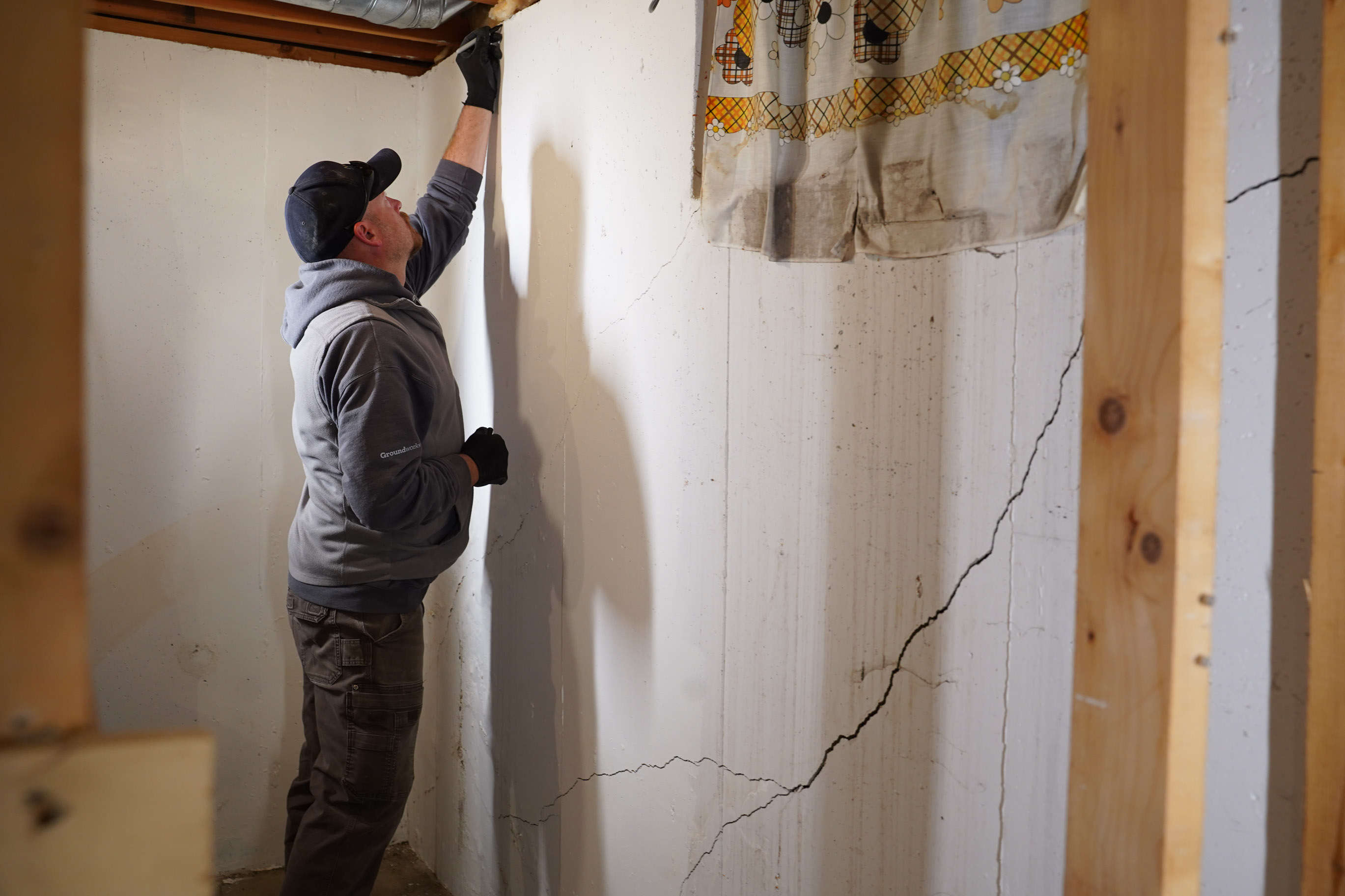 Inspector evaluating a cracked basement wall