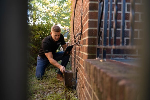 man inspecting house exterior foundation