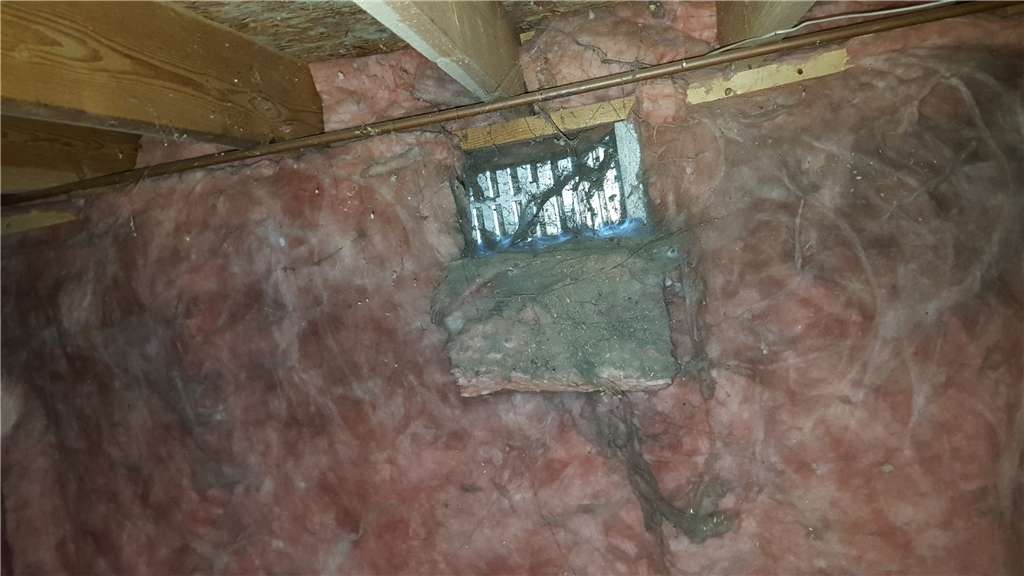 Open crawl space vent surrounded by old insulation