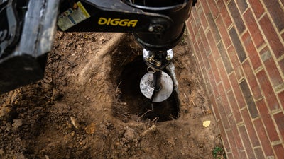 crew installing a helical pier under a house