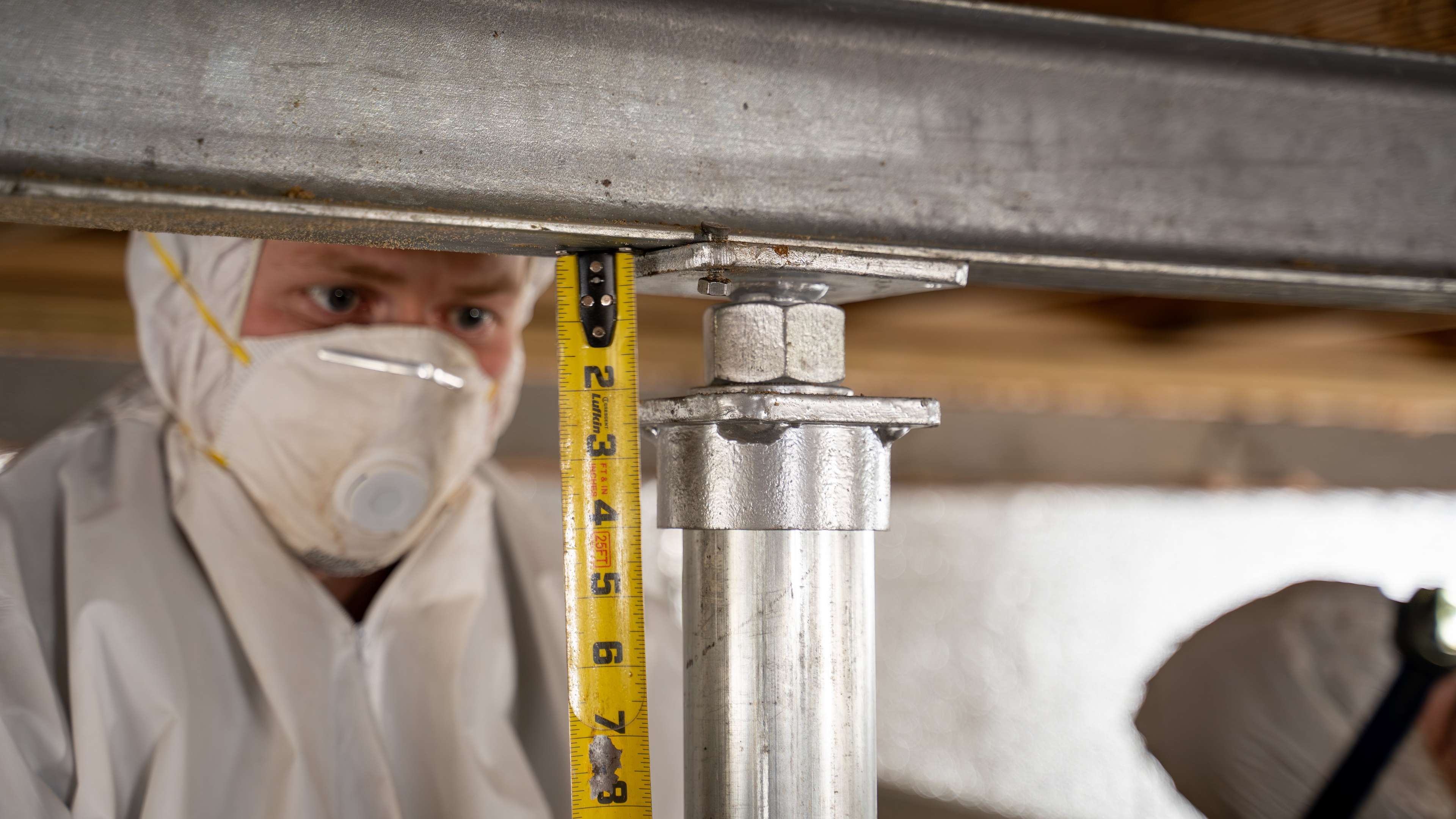 crew member installs a support jack in a crawl space