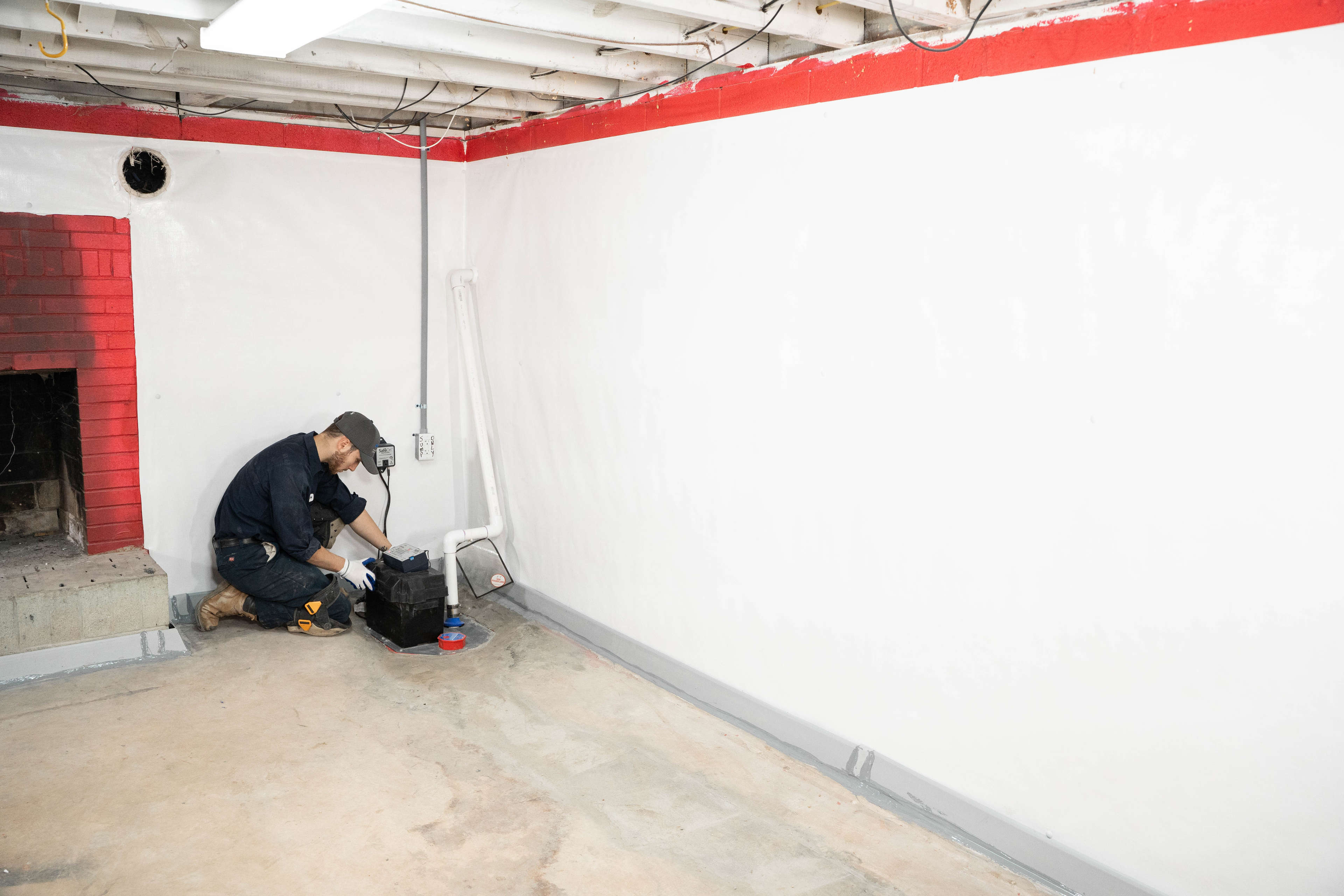 crew member installs sump pump in basement