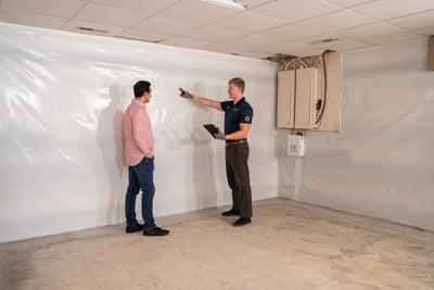 Groundworks inspector showing homeowner a vapor barrier in a basement.