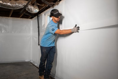crew member installing a basement wall vapor barrier