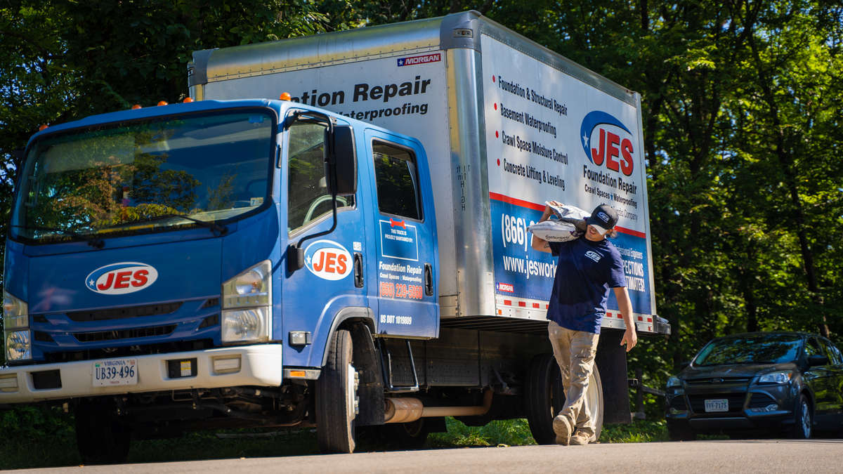JES installer walking next to work truck with materials.
