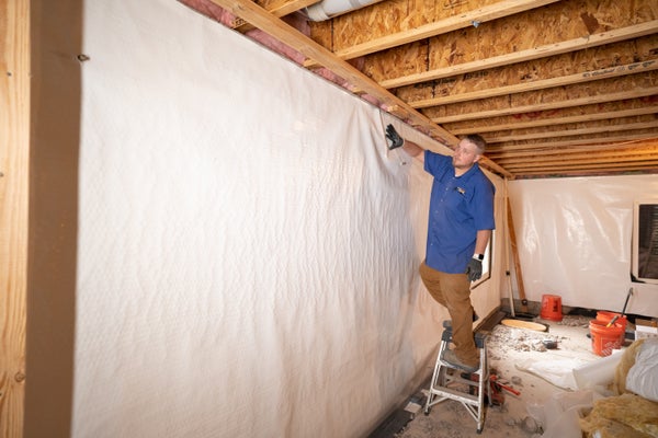 crew installing vapor barrier in basement walls