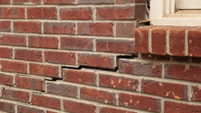 Stair step crack in brick exterior near window.