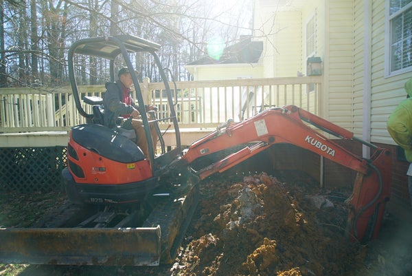 man on bulldozer moving soil near house