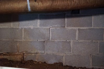 Stair-step crack on a block concrete crawl space wall.