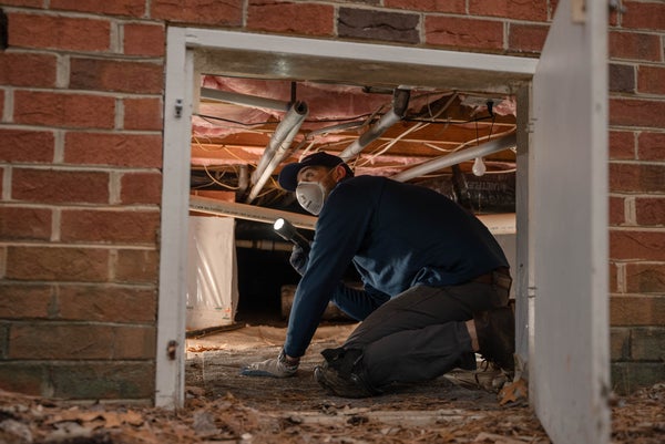 crew member inspecting crawl space beams and piers