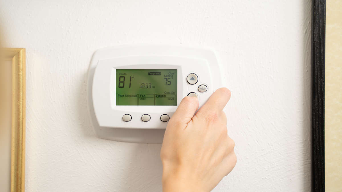 hand adjusting indoor thermostat