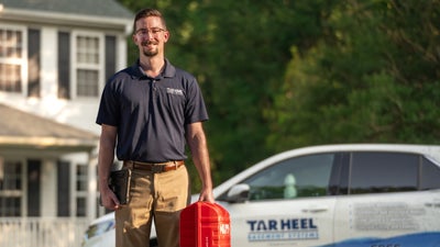 Tar Heel Basement Systems inspector standing by a house and a company car