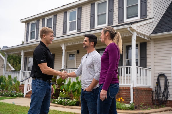 JES inspector shaking hands with homeowner in front of house