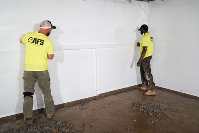 AFS crewmen installing a vapor barrier in a basement.