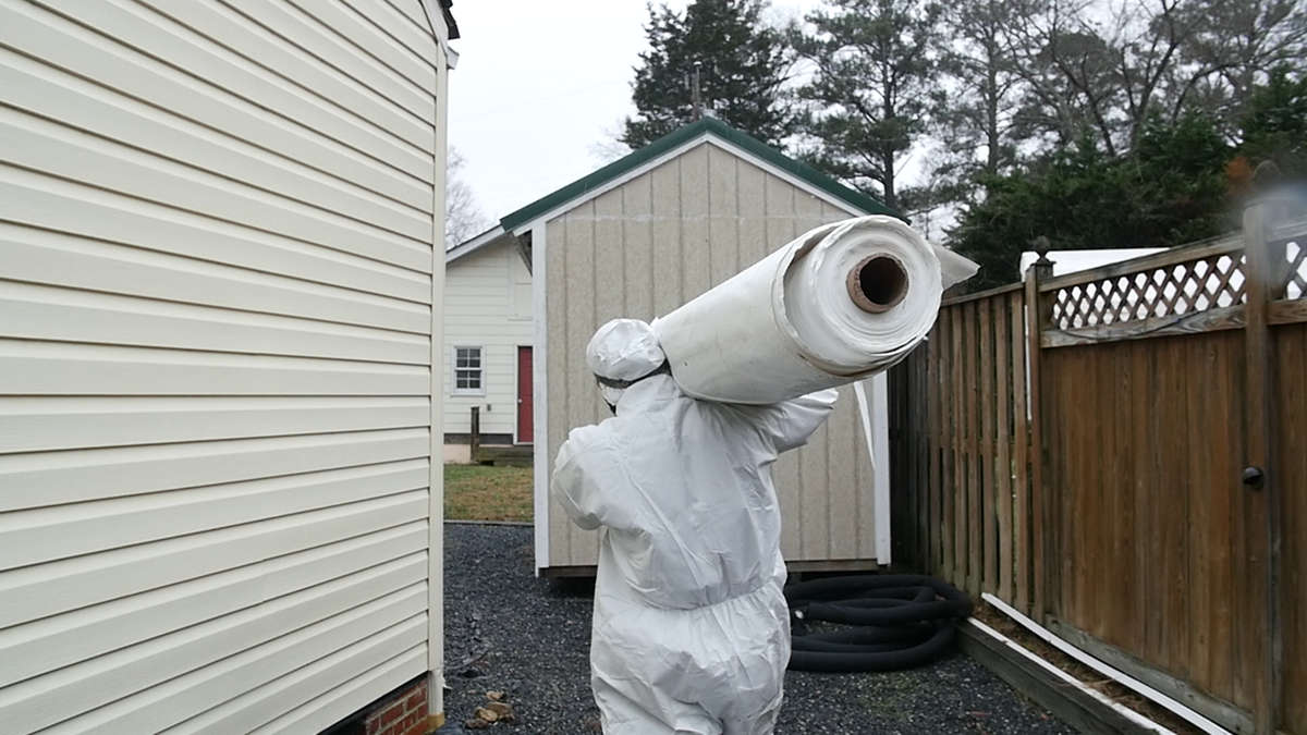 crew member carrying vapor barrier roll