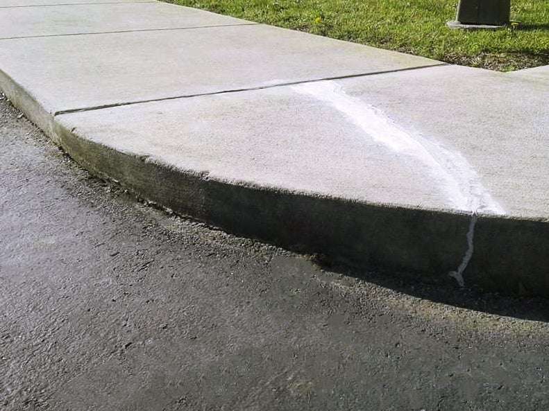 corner of a concrete sidewalk lifted with polyurethane foam