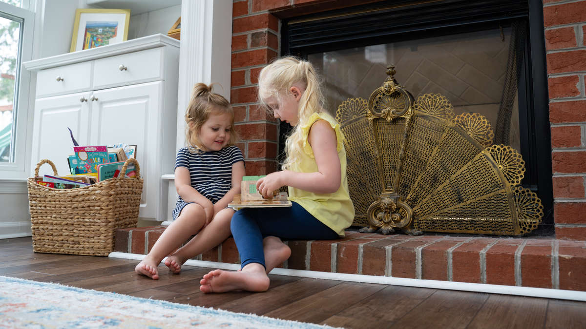 two children sitting beside indoor fireplace