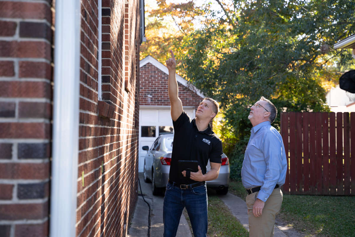 JES inspector pointing to top of house with homeowner