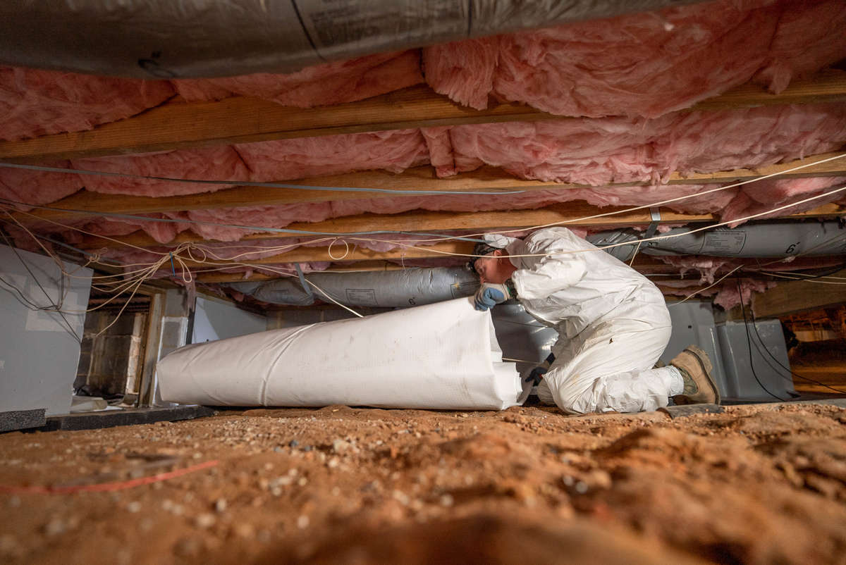 Crew encapsulating crawl space of a home with insulation