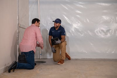Groundworks inspector in basement with homeowner.