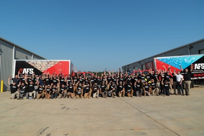 AFS Repair team raising their hands and standing in front of two work trucks
