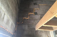 Concrete block wall with expanding foam sealant in zigzag pattern and a wooden shelf on the right.