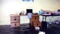 A flooded room with a wooden desk and a table, both partly submerged in water.