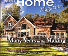 Cover of "Lake and Home" magazine featuring a large lakeside house surrounded by trees.
