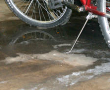 Wet concrete floor and close-up of a bike and kickstand.
