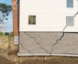 Close-up of cracked basement foundation and separating chimney.