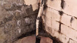 Wet and moldy cinderblock wall and pipe in the basement.