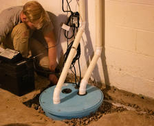 The product crew is installing a backup batter on the sump pump in the basement.