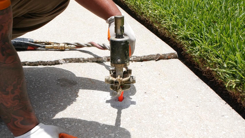 Crew injecting poly into a sidewalk.